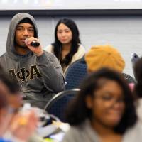 student with microphone asking question while seated at table